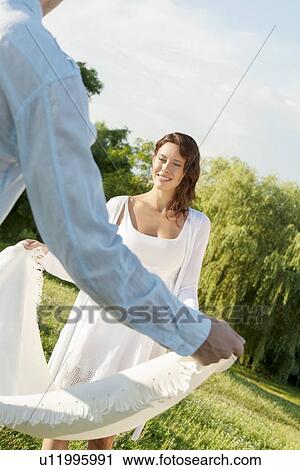 Young woman with man spreading picnic blanket in park View Large Photo Image Stock Image - Young woman with man spreading picnic blanket in park. Fotosearch