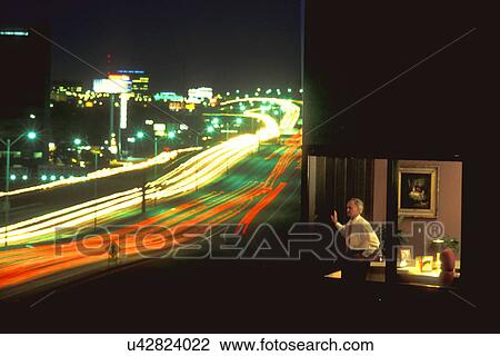 Stock Image - Businessman in Skyscraper Overlooking Freeway at Night. Fotosearch