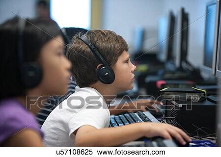 Stock Photography - Children using headphones working in the computer lab at Lovett Elementary School in Houston Texas. Fotosearch