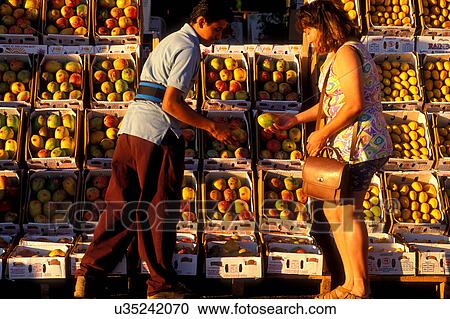 Stock Image - Stock photo of a woman buying a mango from a man at the farmer's market in Houston Texas. Fotosearch