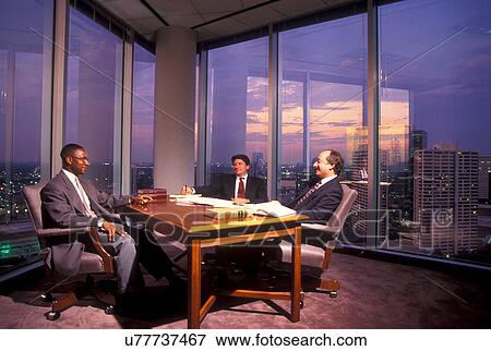 Stock Photo - Stock photo of executices meeting in a corner office with a city view.. Fotosearch