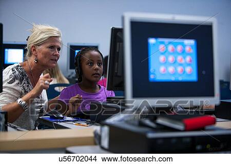 Teacher helping a student in the computer lab at Lovett Elementary School in Houston Texas View Large Photo Image Picture - Teacher helping a student in the computer lab at Lovett Elementary School in Houston Texas. Fotosearch