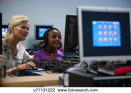 Stock Image - Teacher helping a student in the computer lab at Lovett Elementary School in Houston Texas. Fotosearch