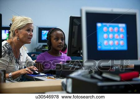 Teacher helping a student in the computer lab at Lovett Elementary School in Houston Texas View Large Photo Image Stock Photo - Teacher helping a student in the computer lab at Lovett Elementary School in Houston Texas. Fotosearch