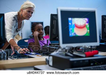 Teacher helping a student in the computer lab at Lovett Elementary School in Houston Texas View Large Photo Image Stock Photo - Teacher helping a student in the computer lab at Lovett Elementary School in Houston Texas. Fotosearch