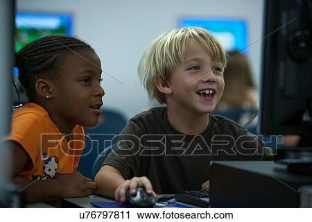 Stock Image - Young boy and girl learning in the computer lab at Lovett Elementary in Houston Texas. Fotosearch