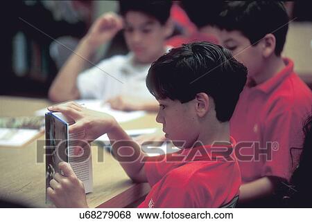 Stock Photo - young boys reading books in the classroom table. Fotosearch