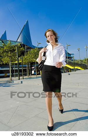 Stock Image - Business woman walking to a meeting . Fotosearch