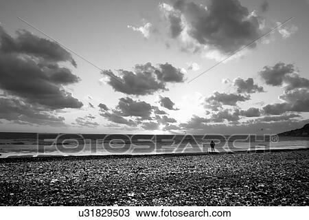 Stock Image - Man standing on the shoreline . Fotosearch