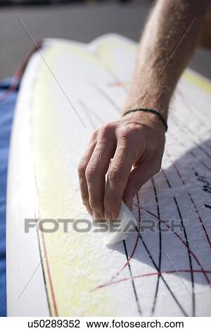Stock Image - Waxing a surfboard . Fotosearch