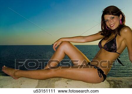 Stock Image - Woman sitting on the shore . Fotosearch