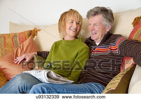 Stock Photo - Adult couple chatting and laughing on sofa. Fotosearch