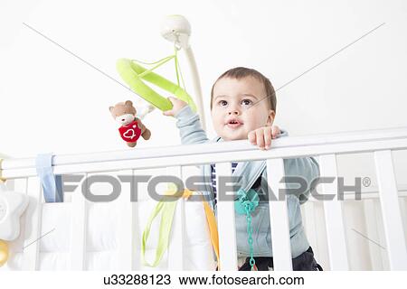 Stock Image - Alert baby boy gazing out from crib. Fotosearch