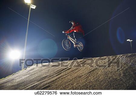 BMX-cyclist jumps his bike at night time View Large Photo Image Stock Photograph - BMX-cyclist jumps his bike at night time. Fotosearch