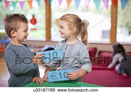 Stock Photo - Boy and girl counting euro currency at nursery school. Fotosearch