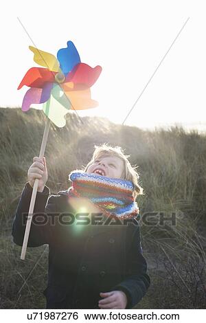 Boy holding up paper windmill at coast View Large Photo Image Stock Photograph - Boy holding up paper windmill at coast. Fotosearch
