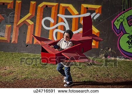 Stock Image - Boy running in toy airplane in park at night. Fotosearch