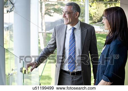 Businessman and woman looking out of office building View Large Photo Image Stock Photo - Businessman and woman looking out of office building. Fotosearch