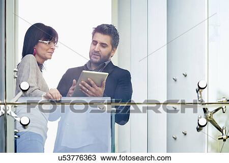 Stock Image - Businessman and woman using digital tablet at balcony. Fotosearch