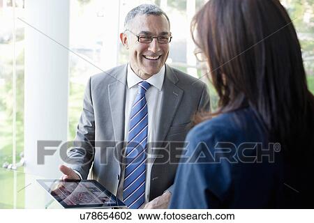 Stock Image - Businessman and woman using digital tablet. Fotosearch