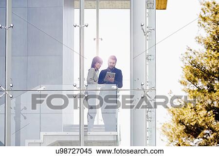 Stock Photography - Businessman and woman using digital tablet at balcony. Fotosearch