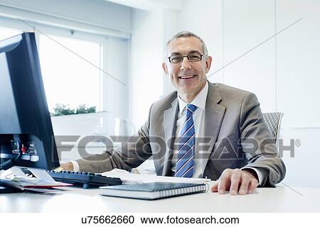 Stock Image - Businessman at office desk. Fotosearch