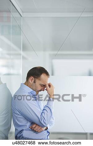 Businessman contemplating against reflective wall View Large Photo Image Stock Photo - Businessman contemplating against reflective wall. Fotosearch