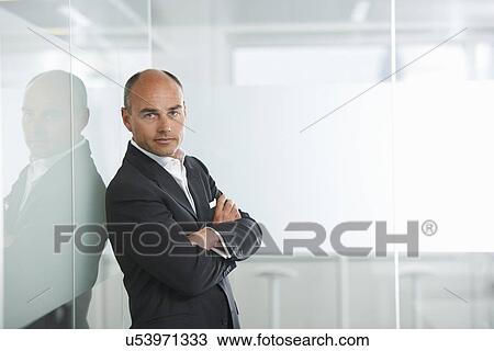 Businessman leaning against reflective wall View Large Photo Image Stock Image - Businessman leaning against reflective wall. Fotosearch