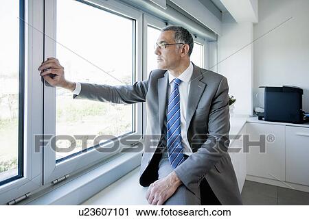 Businessman looking out of office window View Large Photo Image Stock Image - Businessman looking out of office window. Fotosearch