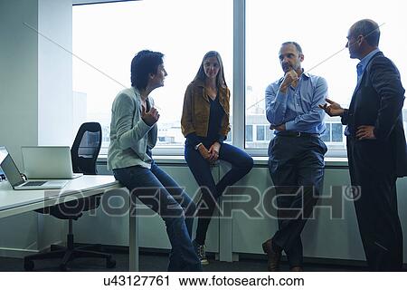 Stock Image - Businesspeople chatting in office. Fotosearch