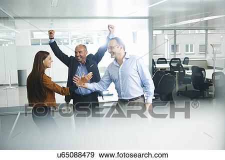 Businesspeople cheering in office View Large Photo Image Stock Photo - Businesspeople cheering in office. Fotosearch