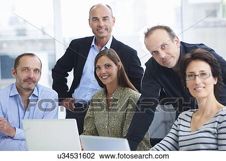 Stock Image - Businesspeople posing for group portrait in office. Fotosearch