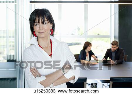 Businesswoman at entrance of meeting room, couple in background View Large Photo Image Stock Image - Businesswoman at entrance of meeting room, couple in background. Fotosearch
