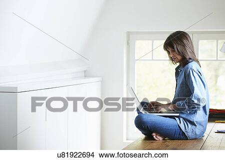 Businesswoman sitting on desk, legs crossed, using laptop View Large Photo Image Picture - Businesswoman sitting on desk, legs crossed, using laptop. Fotosearch