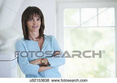 Businesswoman standing in office interior, arms folded View Large Photo Image Stock Photo - Businesswoman standing in office interior, arms folded. Fotosearch