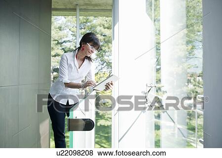 Stock Photo - Businesswoman using digital tablet in corridor. Fotosearch