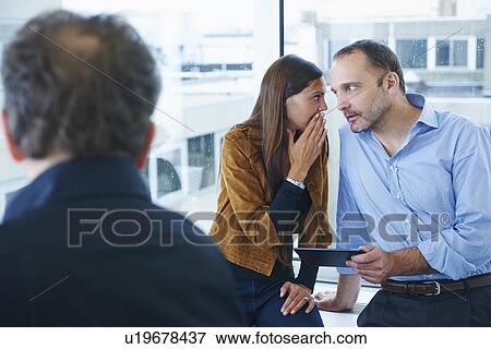 Businesswoman whispering to man in office View Large Photo Image Stock Photo - Businesswoman whispering to man in office. Fotosearch