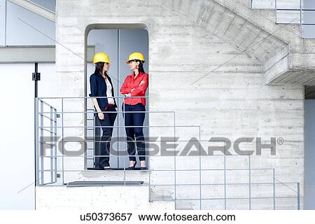 Stock Photo - Businesswomen in safety helmet at balcony. Fotosearch
