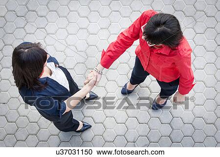 Stock Image - Businesswomen shaking hands. Fotosearch