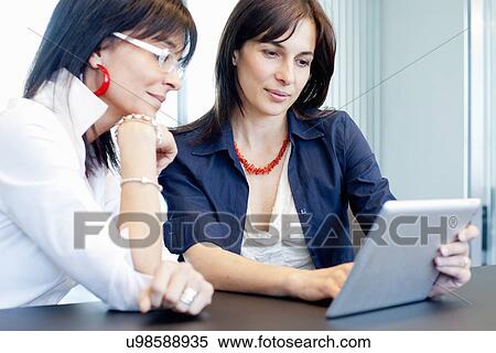 Businesswomen using digital tablet View Large Photo Image Stock Photography - Businesswomen using digital tablet. Fotosearch