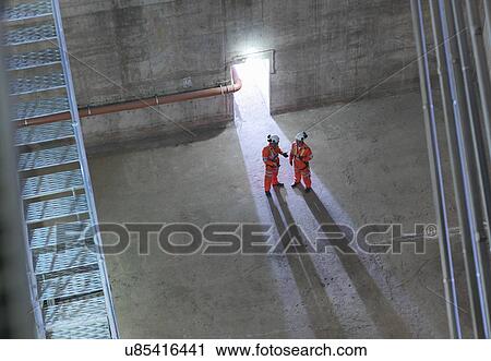 Stock Image - Civil engineers in discussion in suspension bridge, high angle view. The Humber Bridge, UK, built in 1981 was the world's largest single-span suspension bridge. Fotosearch