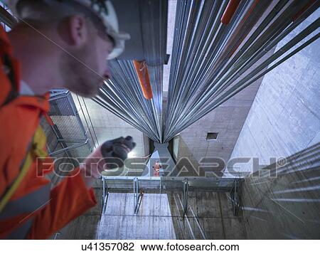 Stock Image - Civil engineers inspecting cable anchorage in suspension bridge, low angle view. The Humber Bridge, UK, built in 1981 was the world's largest single-span suspension bridge. Fotosearch