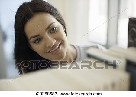 Stock Photo - Close up of young woman searching bookshelves. Fotosearch