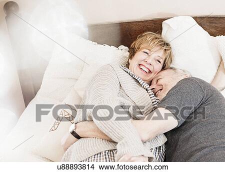 Couple lying on bed laughing View Large Photo Image Picture - Couple lying on bed laughing. Fotosearch