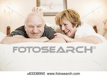 Stock Image - Couple lying on bed, portrait. Fotosearch
