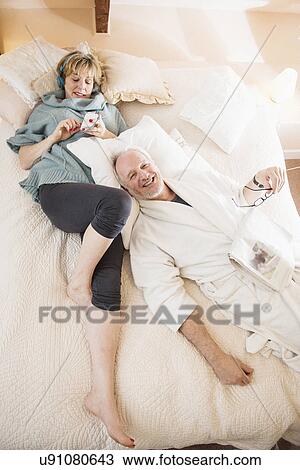 Stock Image - Couple lying on bed relaxing. Fotosearch