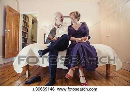 Couple sitting on bed, man putting on shoes View Large Photo Image Stock Photograph - Couple sitting on bed, man putting on shoes. Fotosearch