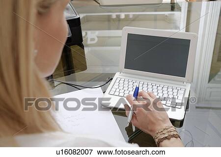 Stock Photo - Cropped close up of young woman typing on laptop at home. Fotosearch