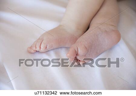 Stock Image - Cropped image of baby girls feet in crib. Fotosearch