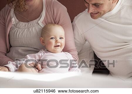 Stock Photograph - Cropped portrait of baby girl and mid adult parents. Fotosearch